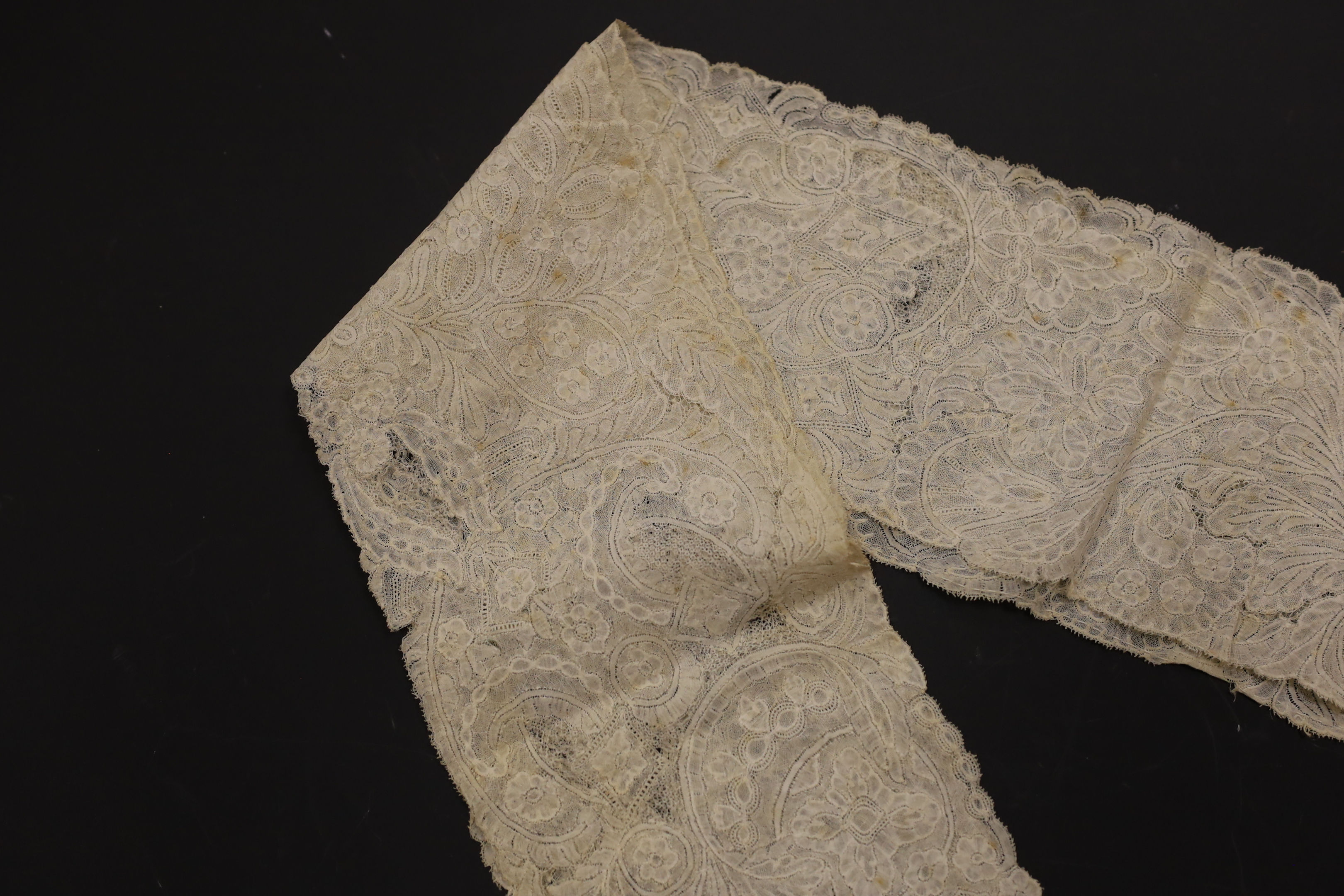 An early 18th century Hollie point insertion baby’s linen vest, three baby bonnets with Hollie point insertions and an early 18th century pair of Flemish bobbin lace lappets, a partly finished needlepoint length of lace,